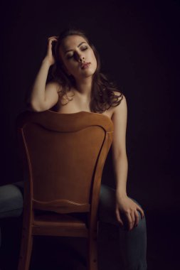 Karanlık odada gür saçlı lüks üstsüz kadın