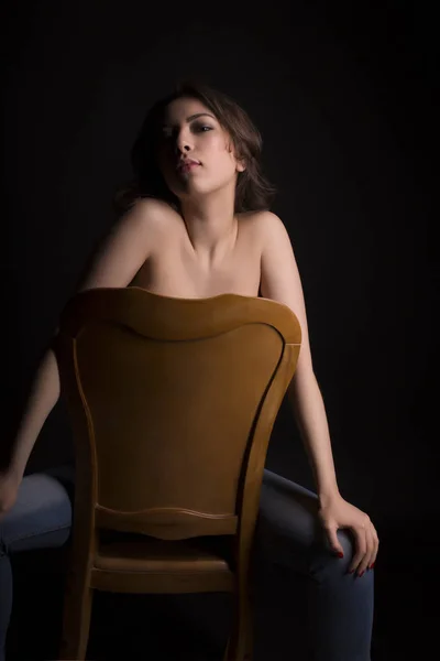 Gloriosa mulher topless em jeans azul sentado em uma cadeira — Fotografia de Stock