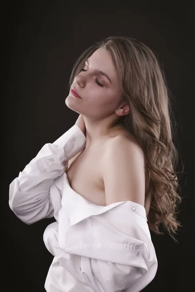 Tenderlady with lush hair in shirt on a dark background