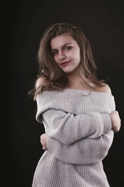 Улыбающаяся молодая женщина позирует в свитере с голыми плечами — стоковое фото