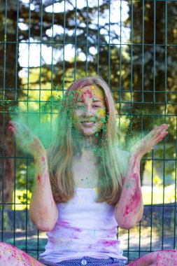 Yeşil toz Holi parkta savurma sarışın genç kadın