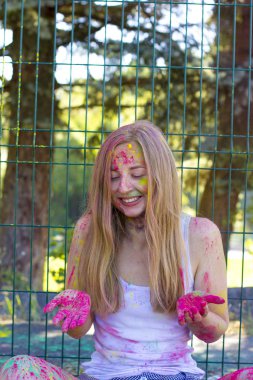 Mutlu genç kadın pembe toz Holi parkta yukarı atma