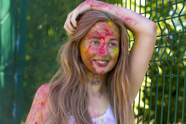 Ευτυχισμένος ξανθιά γυναίκα με πολύχρωμα σκόνη Holi στο πρόσωπό της — Φωτογραφία Αρχείου
