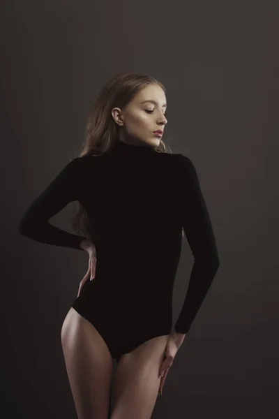 Model test with seductive woman in black body over a grey studio