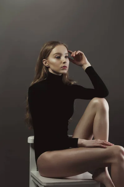 Modellversuch mit sinnlicher Frau in schwarzem Körper, die auf dem Stuhl sitzt — Stockfoto