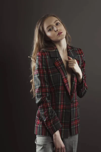 Gyönyörű fiatal nő pózol a modellkísérletek kockás kabát — Stock Fotó