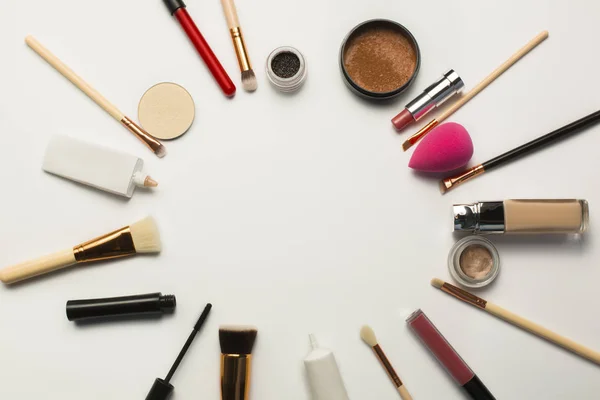 Flat lay of concealer,makeup brushes and bronzer over a white ba — Stock Photo, Image