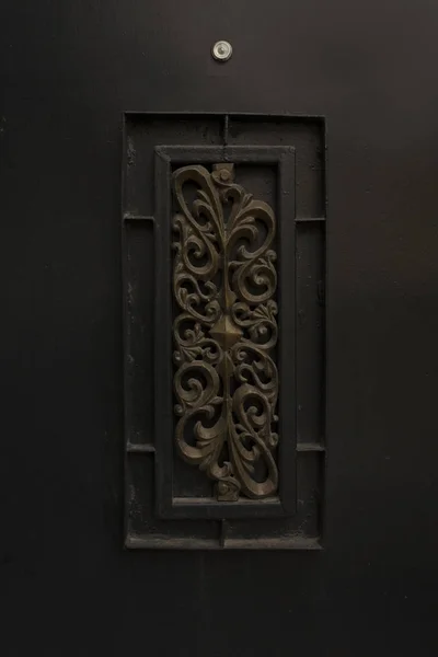 Крупный план черной кованой железной двери с глазком — стоковое фото