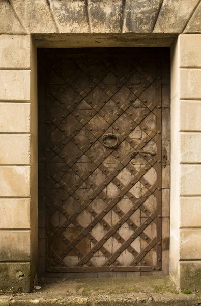 Древняя деревянная дверь с металлическими элементами и ржавой ручкой — стоковое фото