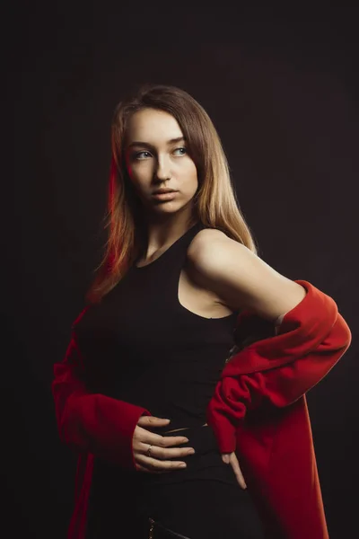 Fashionable young woman in red coat at studio — Stock Photo, Image