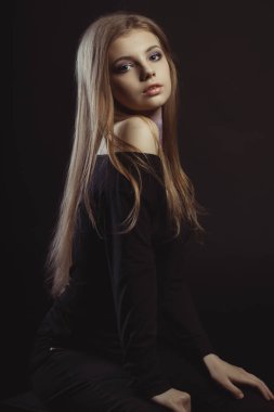 Beautiful young woman with long blonde hair on a black backgroun clipart