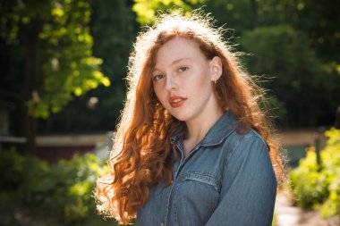 Güzel kızıl saçlı modeli par, güneş ışınlarının kot gömlek