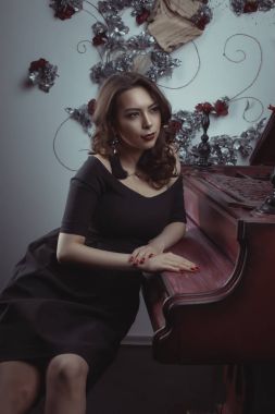 Güzel esmer modeli Studio piyanoda oturan