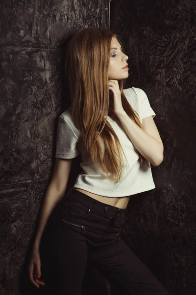 Красивая молодая женщина с длинными светлыми волосами позирует в темной комнате — стоковое фото