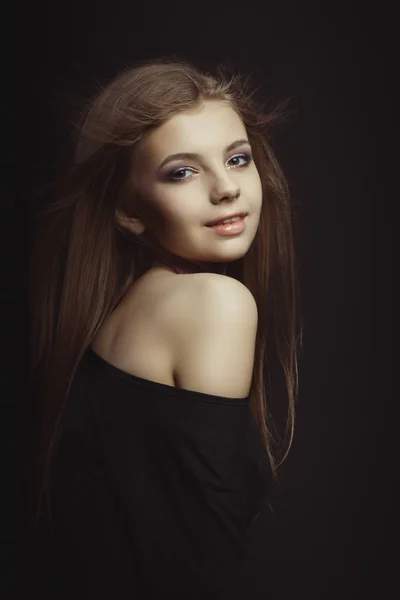 Smiling young model in black dress posing at studio — Stock Photo, Image