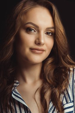 Esmer kıvırcık saçlı genç model siyah bir backgr üzerinde gülümseyen