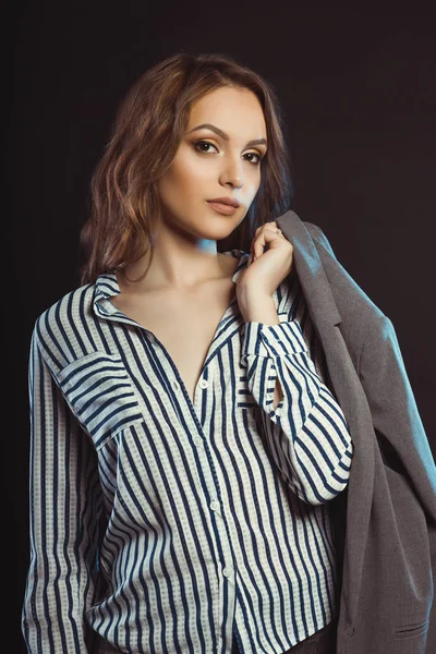 Glamor brunette model posing in shirt and holding her jacket — Stock Photo, Image