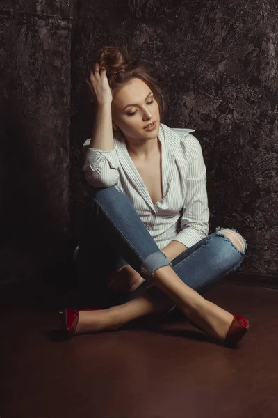 Znakomity młoda kobieta koszula i jeansy, siedząc na podłodze — Zdjęcie stockowe