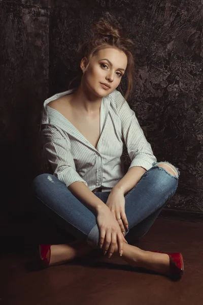 Erstaunliche junge Frau in Hemd und Jeans auf dem Boden sitzend — Stockfoto
