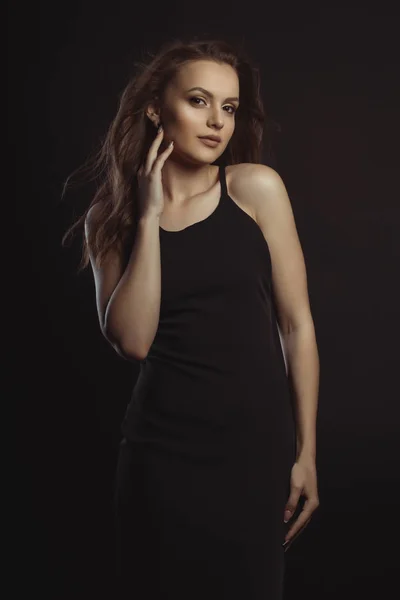 Όμορφη μελαχρινή μοντέλο σε μαύρο φόρεμα που ποζάρουν στο studio — Φωτογραφία Αρχείου
