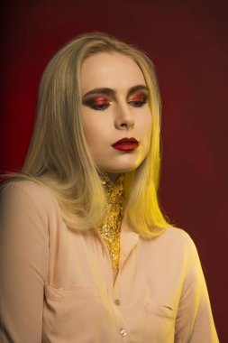 Parlak makyaj ve altın folyo ile baştan çıkarıcı genç kadın. Kırmızı bir