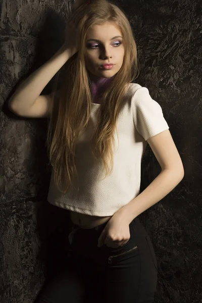 Maravillosa joven con el pelo largo y rubio posando en habitación oscura — Foto de Stock