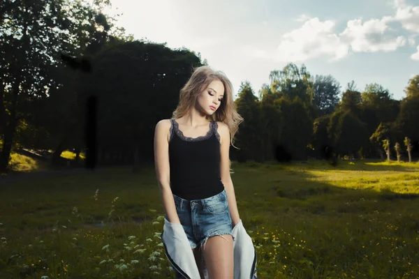 Divatos fiatal modell pózol a parkban egy napfényes nap, összegezve — Stock Fotó
