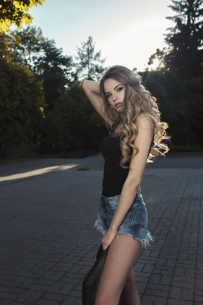 Modieus model met weelderige krullend haar en poseren in het park op — Stockfoto