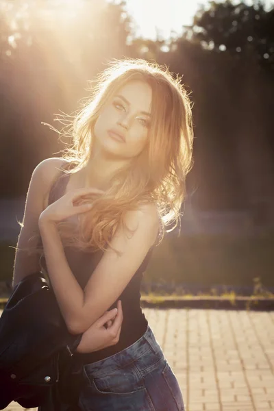 Hermosa joven modelo con exuberante cabello ondulado posando en rayos de sol —  Fotos de Stock