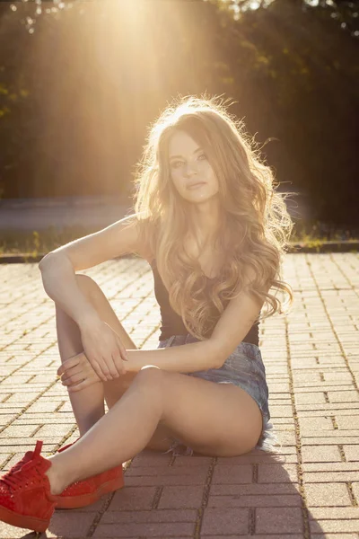 Mooie blonde model gekleed in trendy kleding, zittend op de pav — Stockfoto