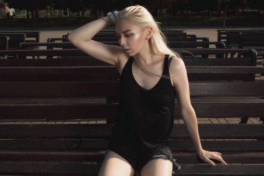 Güneşli bir günde bir bankta poz sarışın model şık giyinmiş