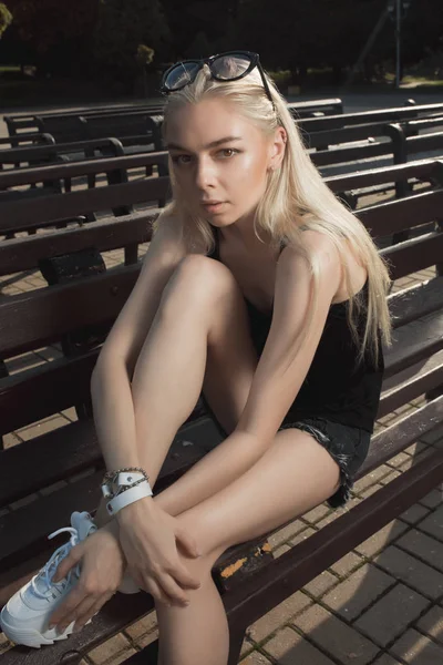 Fashionabla blond modell i snygga kläder poserar på en bänk i — Stockfoto