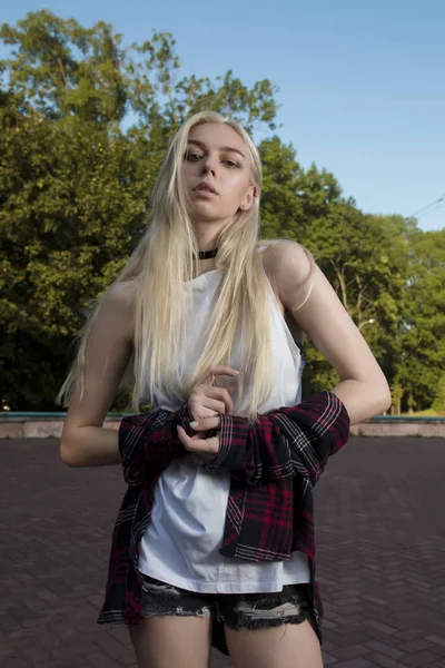 Vacker blond modell i snygga kläder poserar i parken — Stockfoto