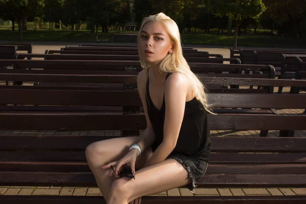 Привлекательная блондинка в повседневной одежде позирует на скамейке в r — стоковое фото