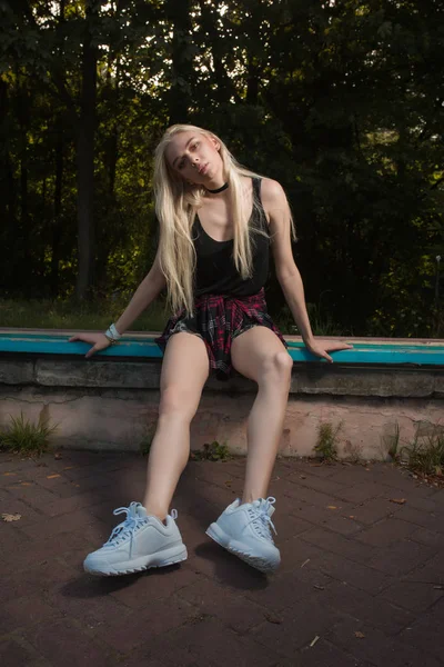 Uzun sarı saçlı bir bankta poz çekici genç kadın