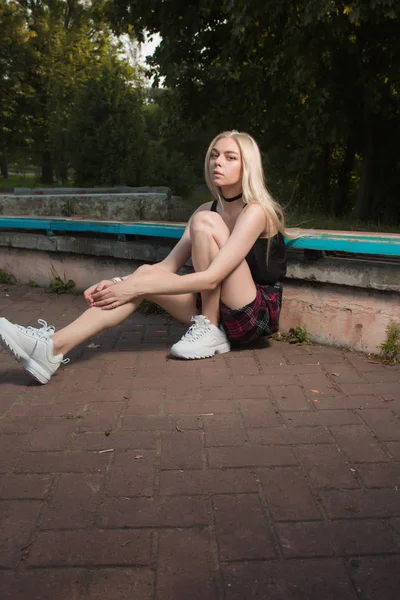 Vacker blond modell i fashionabla kläder poserar på en bänk — Stockfoto