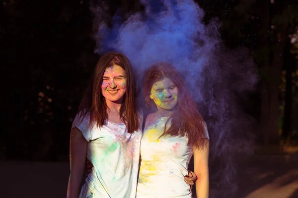 İki kadın bir kuru renk arka plan üzerinde Gulal toz kucaklamak. — Stok fotoğraf