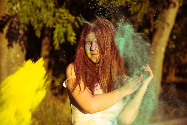 Szczęśliwa młoda kobieta z długimi włosami, grając z kolorowe pow Gulal — Zdjęcie stockowe