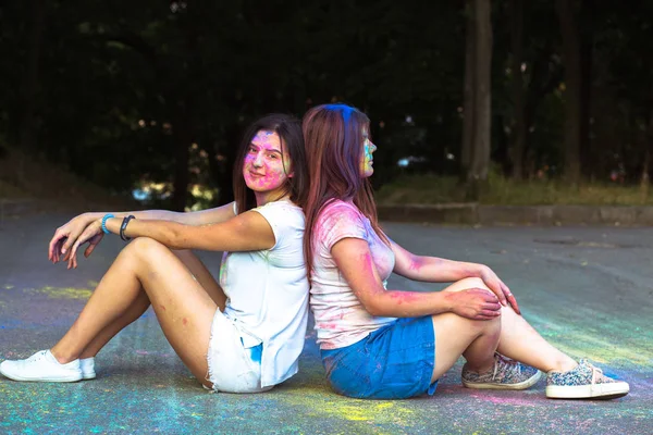 Duas mulheres morenas estão sentadas no asfalto coberto seco Gulal — Fotografia de Stock