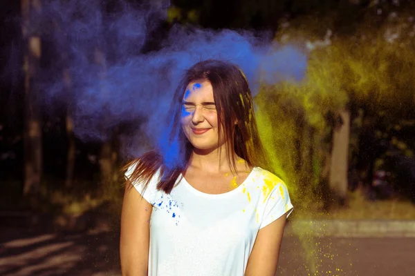 Hermosa mujer joven con polvo seco azul y amarillo Gulal en h — Foto de Stock