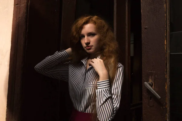 Modelo de pelo rojo triste con el pelo largo y exuberante. Mujer posando en un viejo —  Fotos de Stock