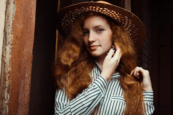 Beautiful redhead woman with long curly hair in straw hat posing — Stock Photo, Image