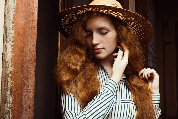 Beautiful redhead model with closed eyes in straw hat posing in — Stock Photo, Image
