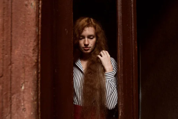Modelo de cabelos vermelhos triste em pé atrás de uma porta de vidro fechada. Raindr. — Fotografia de Stock