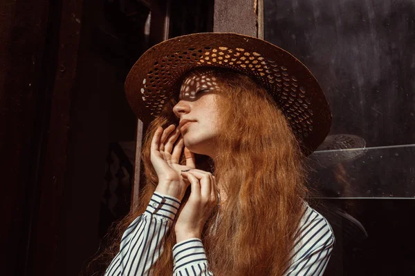 Портрет красивої рудої волохатої жінки в солом'яному капелюсі з тіні — стокове фото