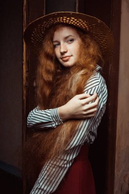 Hasır şapka poz içinde uzun dalgalı saç modeliyle zarif Kızıl saçlı