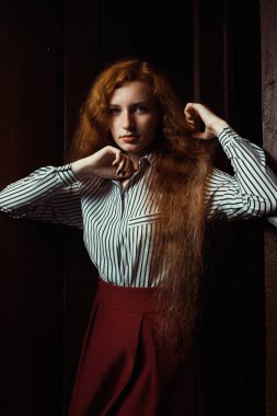 Güzel genç kırmızı saçlı model beyaz giyen çizgili gömlek ve