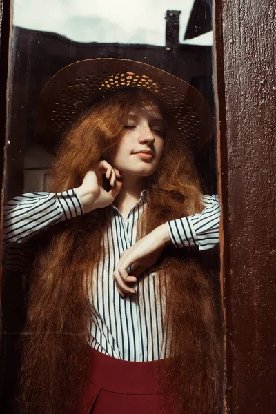 나무 문 뒤에 밀 짚 모자에 아름 다운 젊은 빨간 머리 여자 — 스톡 사진