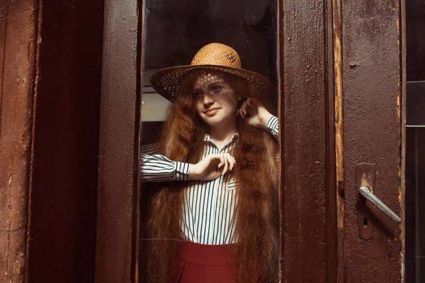 Lächelndes junges rothaariges Model mit Strohhut und Schatten auf dem Kopf — Stockfoto