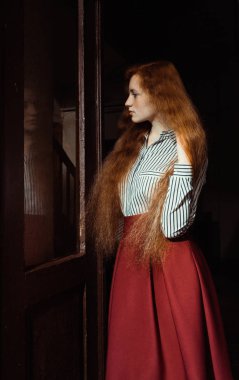 Güzel genç zencefil modeli kıvırcık kırmızı saçlı ve çilli stand ile